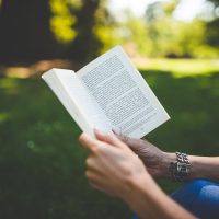 一位编辑在台灯下整理读者来信与勘误记录，纸页按主题分类叠放，暖光与深色桌面形成对比，气氛沉稳